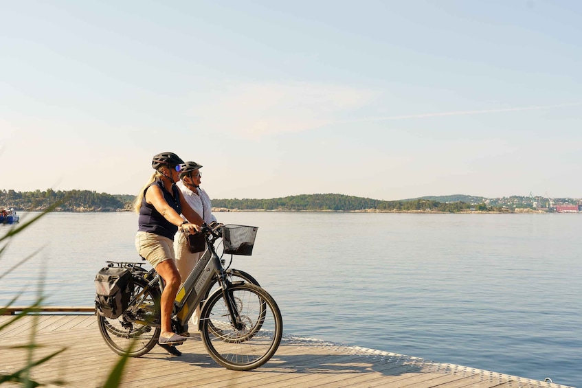 Two people on a dock by a lake with a bicycle. 1