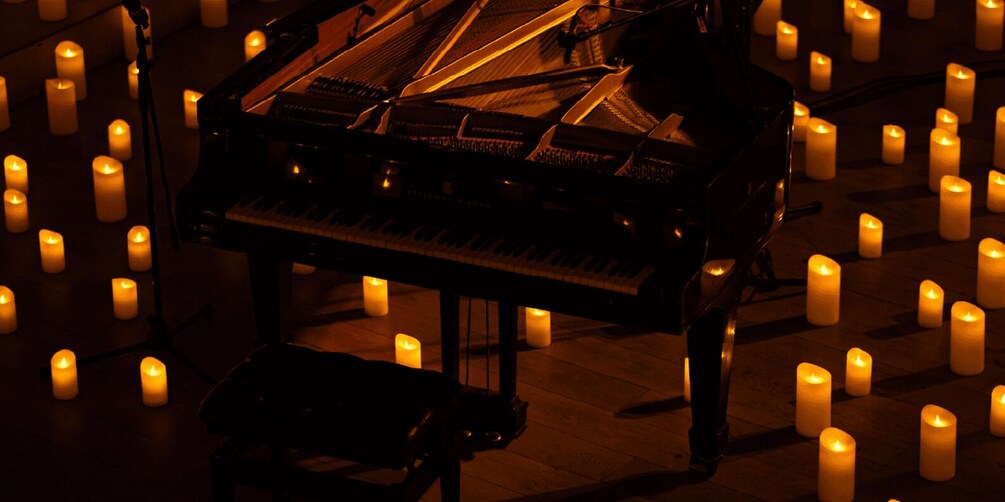 A grand piano surrounded by lit candles. 1