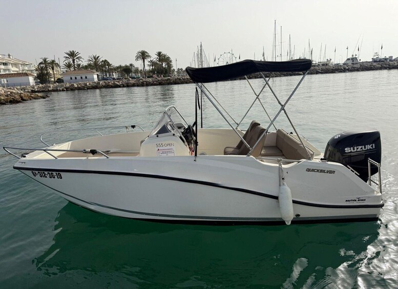 A white motorboat with a Suzuki outboard motor, a canopy, and a cabin with seating. 3