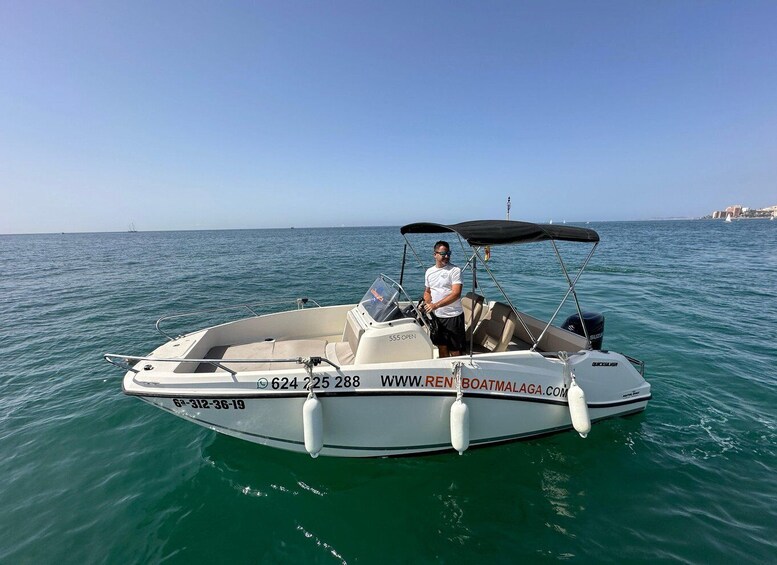 A small motorboat on calm waters with a person standing at the helm. 4