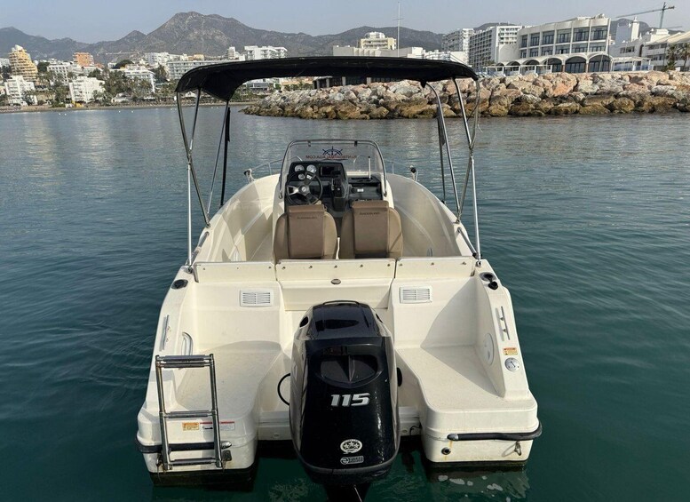 A white motorboat with a black canopy, a steering wheel, and a 115 horsepower outboard motor. 5