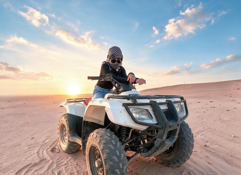 Una persona guida un ATV in un paesaggio desertico al tramonto. 1