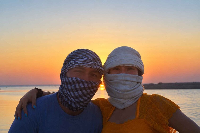 Two people standing close together with a sunset in the background. 4