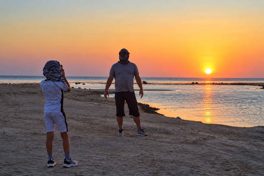Two people on a beach at sunset, with the sun low on the horizon. 3