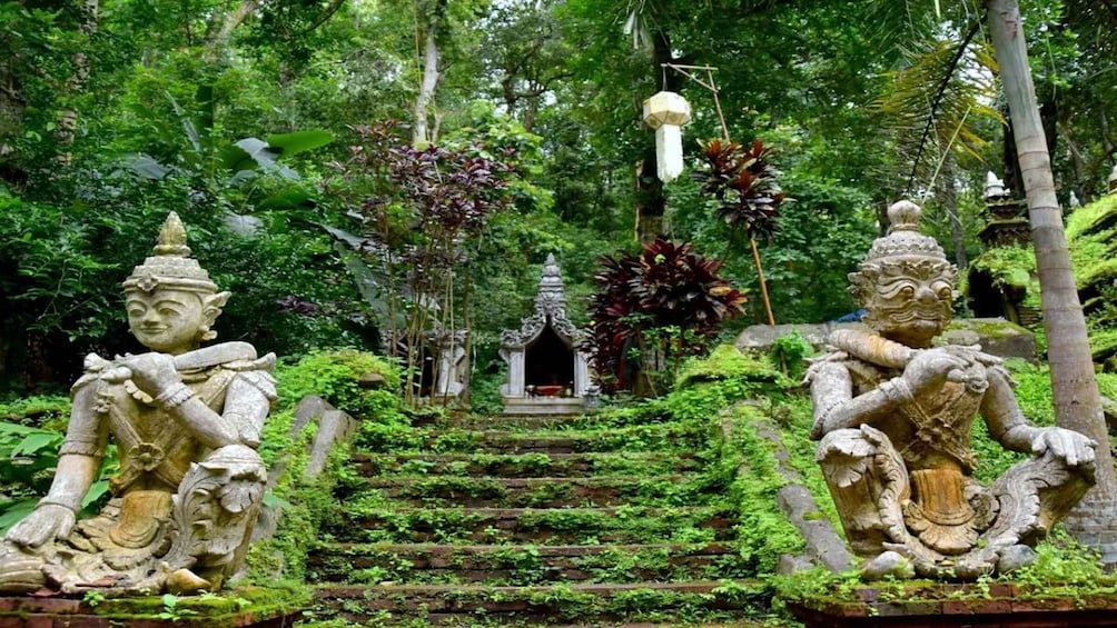A temple complex with stone statues and a central shrine surrounded by lush greenery. 2