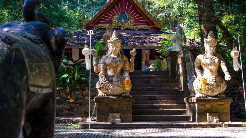 A temple with two large statues of deities, a staircase leading to the temple entrance, and a peacock statue. 5