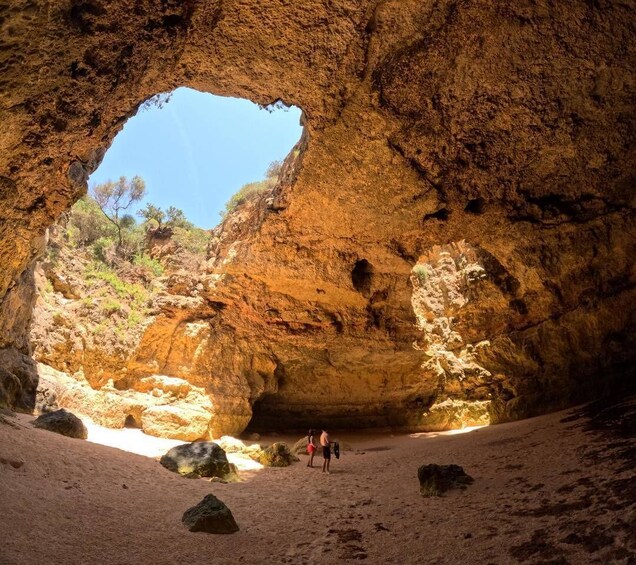A large rock arch with people standing inside. 1