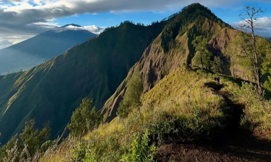 A mountain landscape with a clear sky and a path leading up the slope. 2