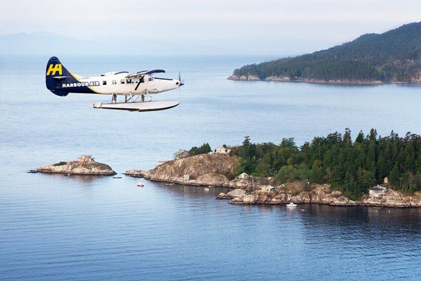 Un hidroavión sobre una zona costera con islas rocosas y bosques densos. 5