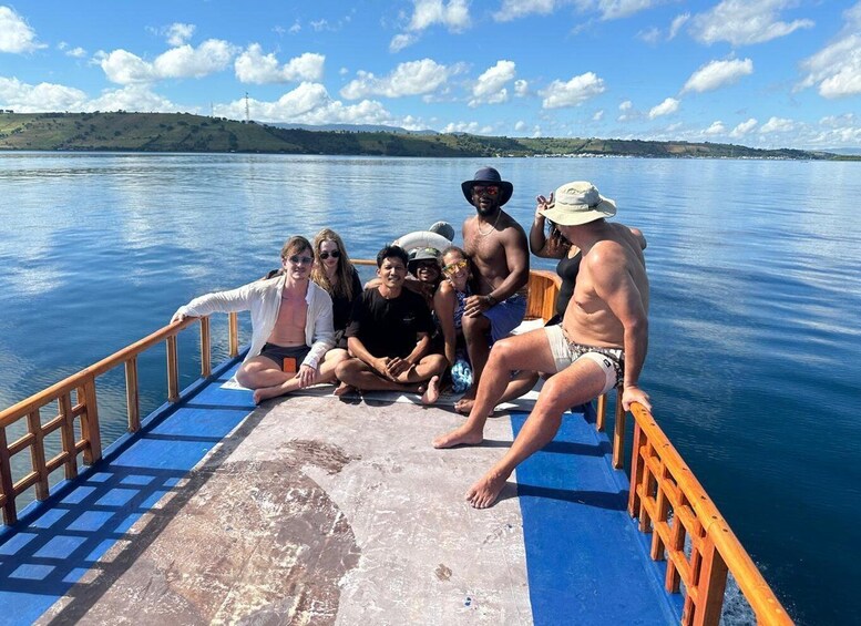 A group of people on a boat with a calm lake and distant hills. 2
