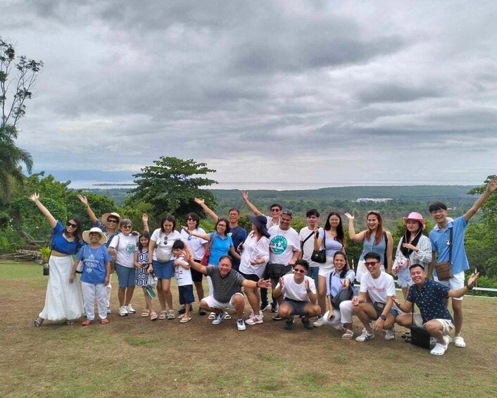 A group of people posing for a photo in a grassy area with trees and a cloudy sky in the background. 2