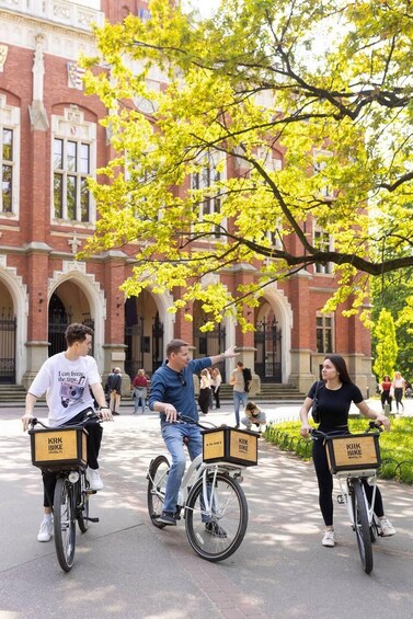 Kolme ihmistä pyöräilee, ja heidän pyöriensä takana on tavaralaatikot, joissa lukee «KRK BIKE». Taustalla näkyy punatiilinen rakennus. 3
