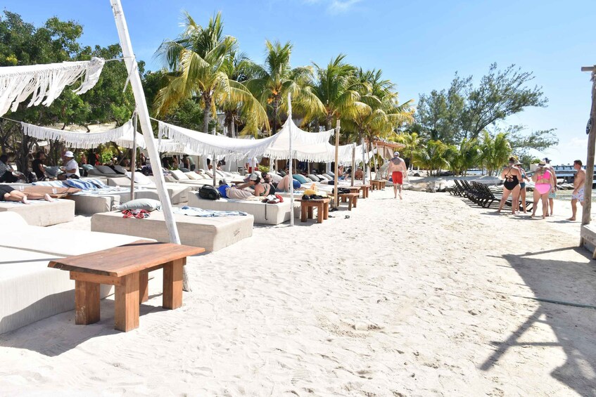 A beach with lounge chairs and umbrellas under white canopies. 2
