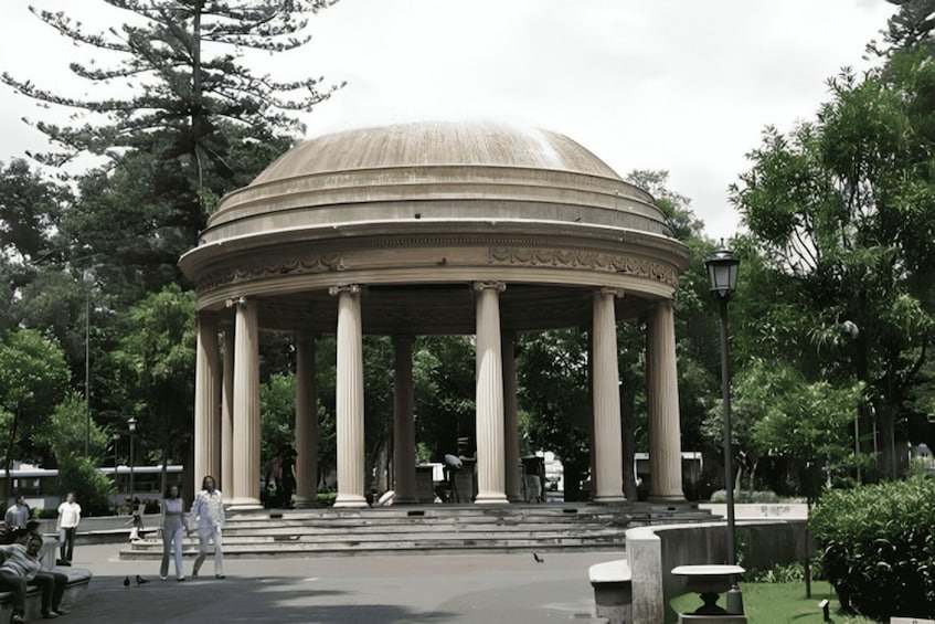 A classical pavilion with a dome and columns, surrounded by trees and benches. 5