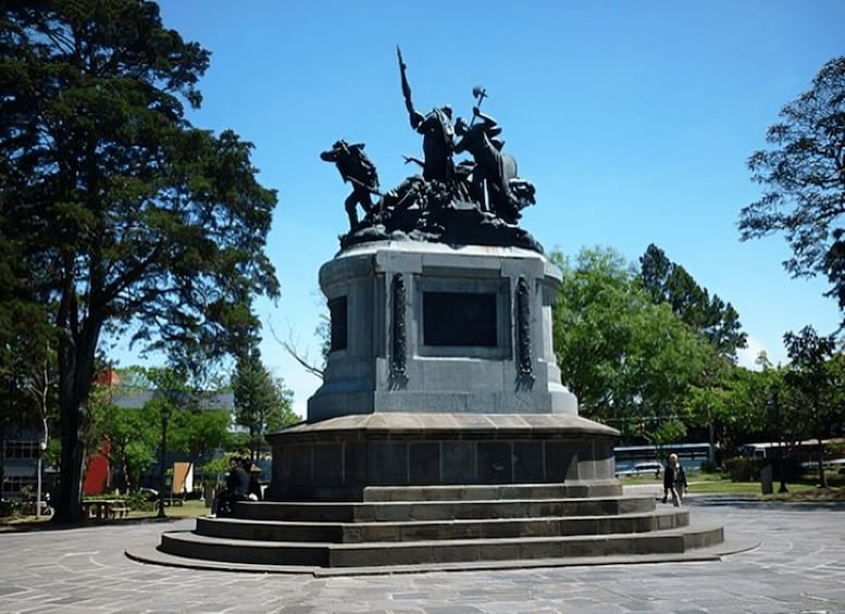 A statue of soldiers on horseback in a park with trees and a clear sky. 4