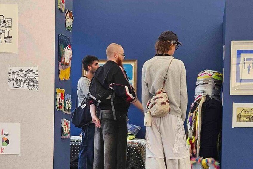 Menschen gehen durch eine Kunstgalerie, in der verschiedene Kunstwerke ausgestellt sind. 4