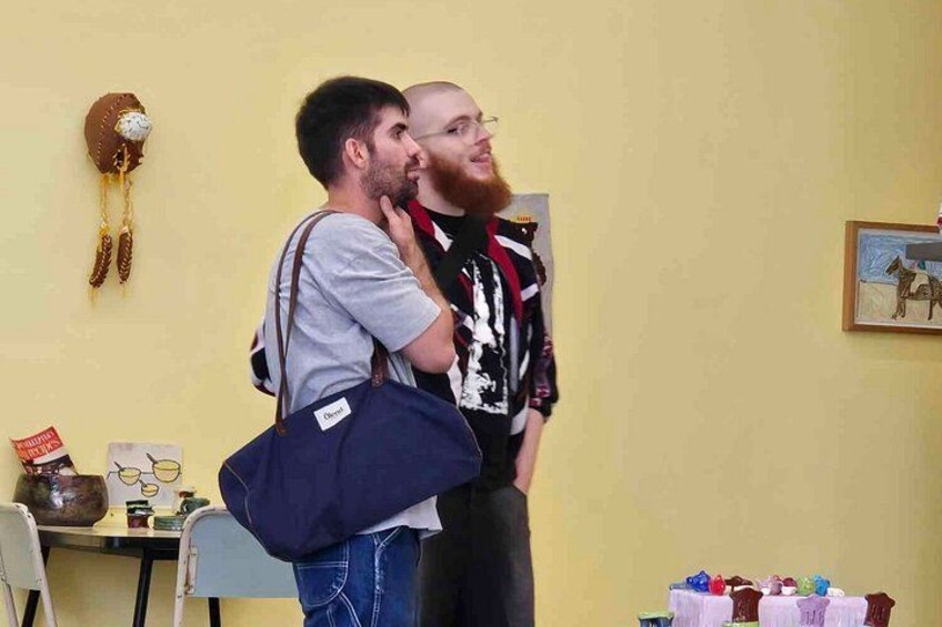 Zwei Personen im Innenbereich, eine trägt ein gestreiftes Hemd und die andere ein graues T-Shirt. 2