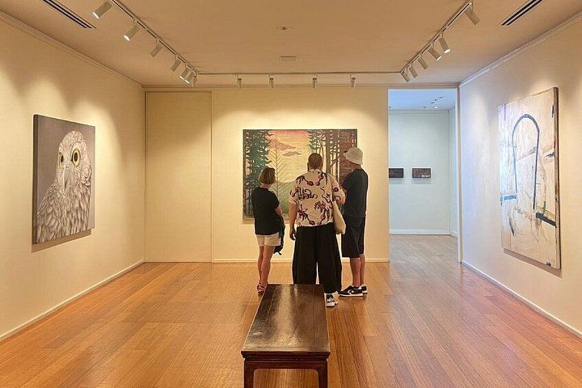 Eine Kunstgalerie mit Holzböden und Gemälden an den Wänden. 1
