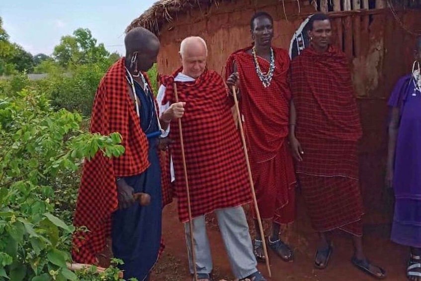 A group of people in traditional attire standing in front of a hut. 3