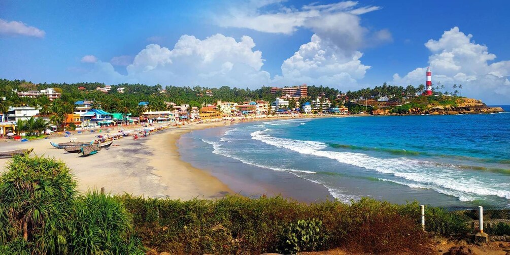 A beach with a lighthouse, ocean waves, and buildings along the shore. 2