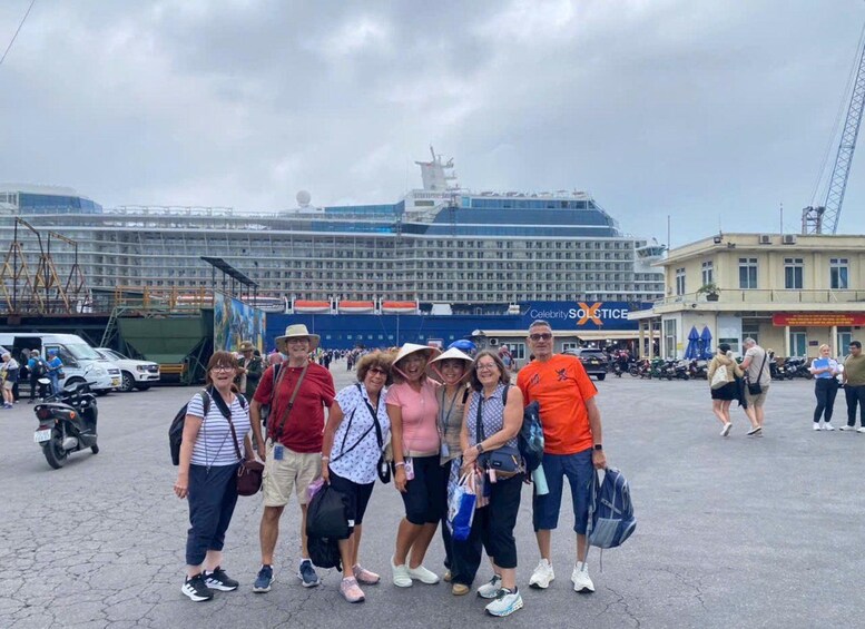 A group of people posing in front of a cruise ship and a building with a sign that reads 'Celebrity SOLTICE.' 5