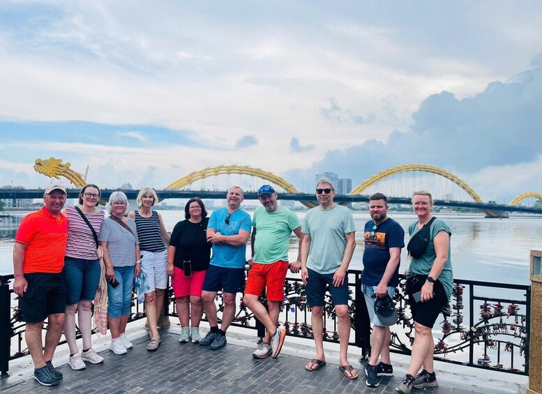 A group of people standing on a dock with a river and a bridge in the background. 4