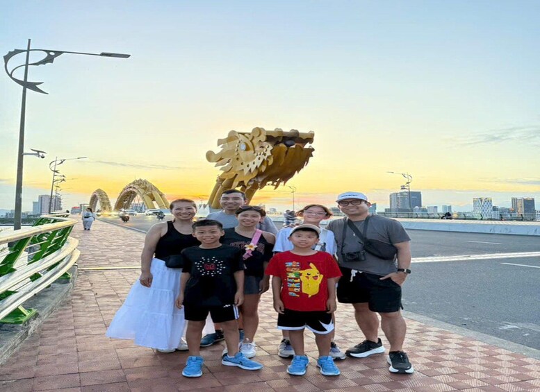 A group of people standing on a bridge with a dragon sculpture in the background. 2