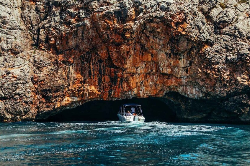 A boat navigating through a rocky cave entrance. 2