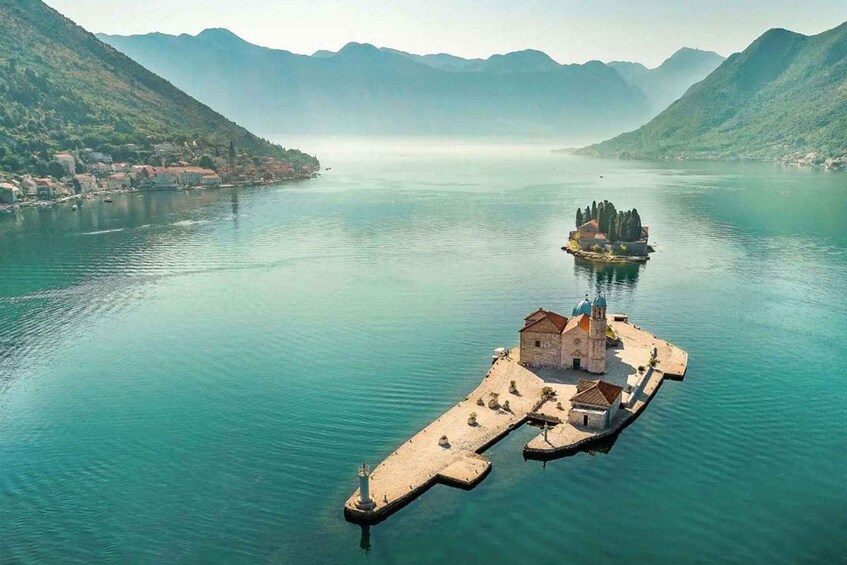 A serene lake with a small island featuring a church and a lighthouse. 3