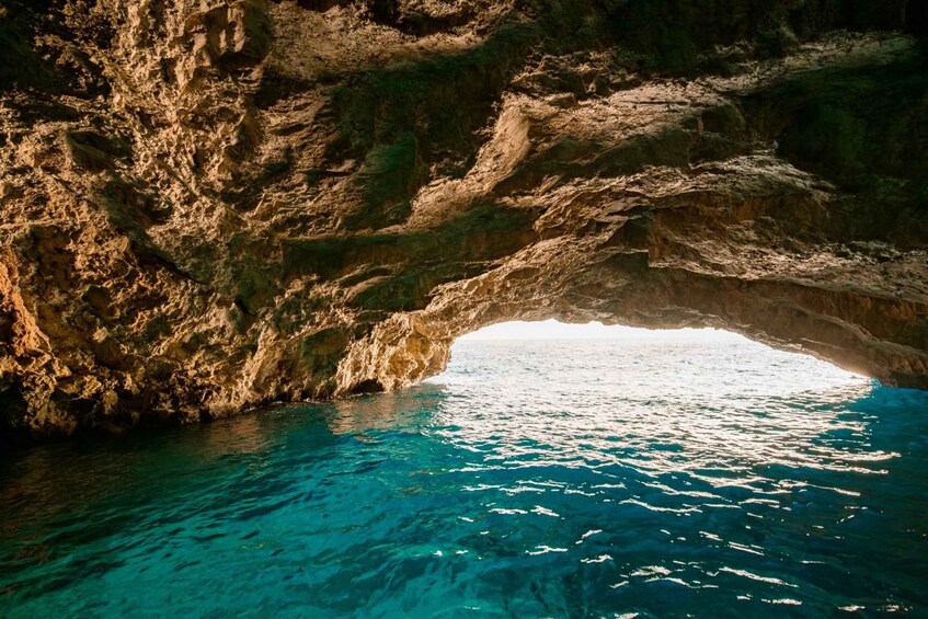 A rocky cave entrance with clear blue water. 1