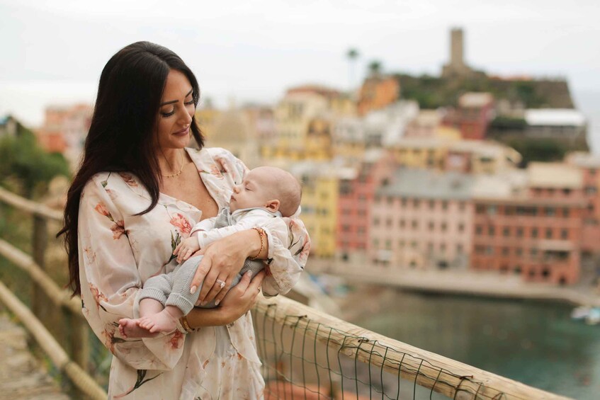 Une personne tenant un bébé sur un pont, avec une vue sur la ville en arrière-plan. 2