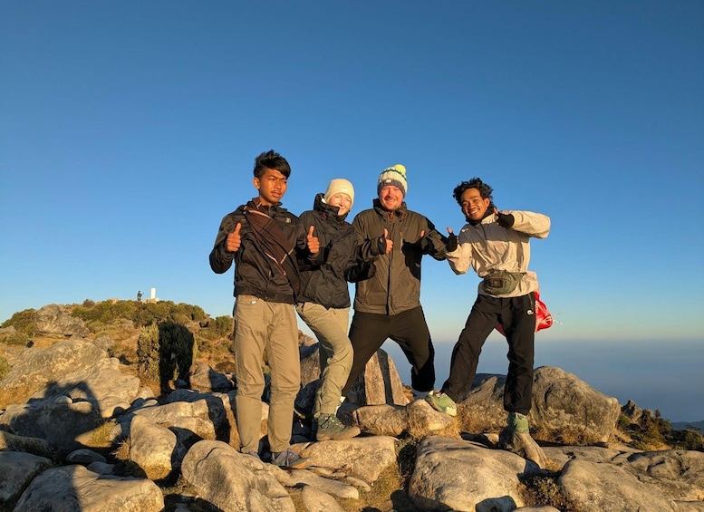 Four people standing on rocky terrain with a clear sky. 3