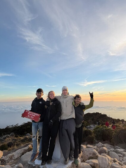 A group of people standing on a rocky outcrop with a clear sky and distant clouds. 4