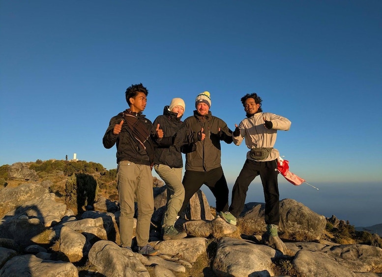 Four people standing on rocky terrain with a clear sky. 2