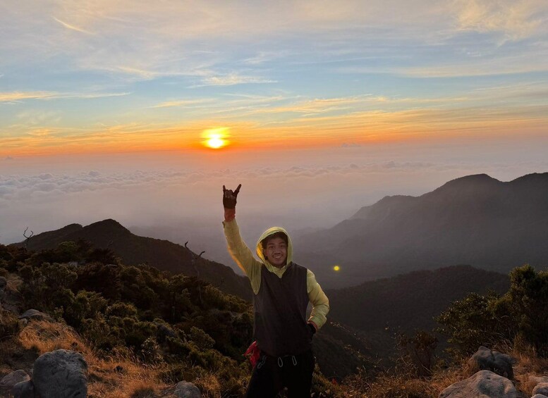 A person standing on a mountain peak with a sunset in the background. 3