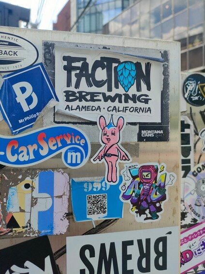 A sign for Faction Brewing in Alameda, California, with various stickers and a QR code. 3