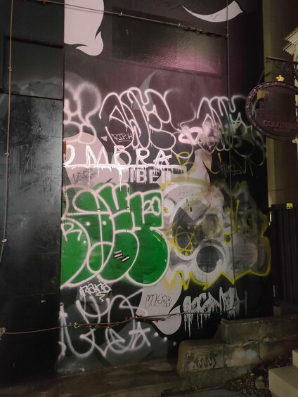 A wall covered with graffiti, including the words "JUMPA" and "JUMPA BIBLIET". 1