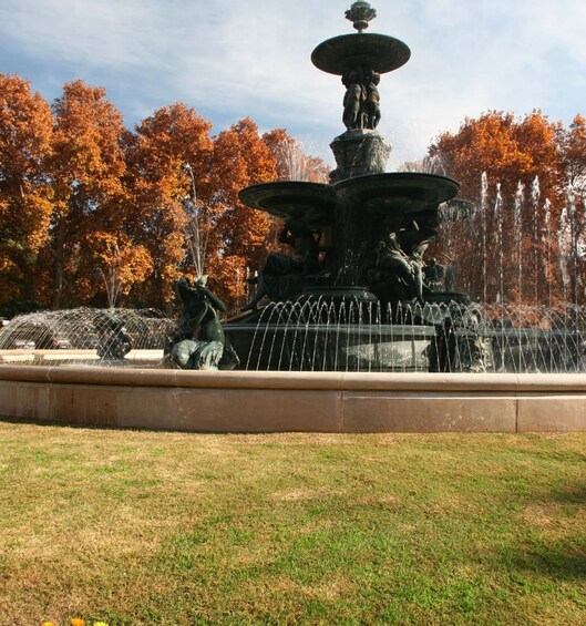 A multi-tiered fountain with water jets in a park with autumn trees. 3