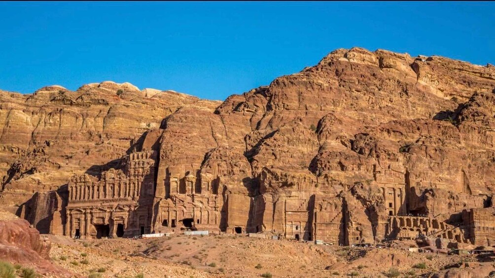 A large sandstone rock formation with carved ancient structures. 5