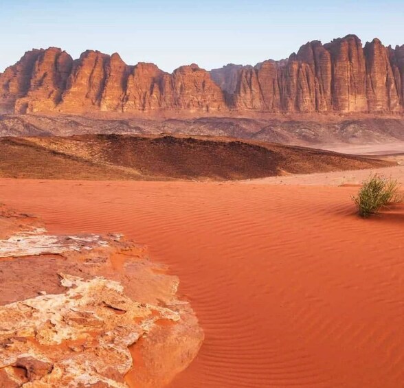 A desert landscape with red sand dunes and a rocky mountain range in the background. 3
