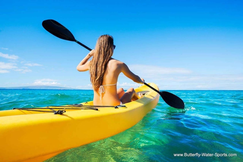 A person kayaking on a yellow kayak in clear blue waters. 3