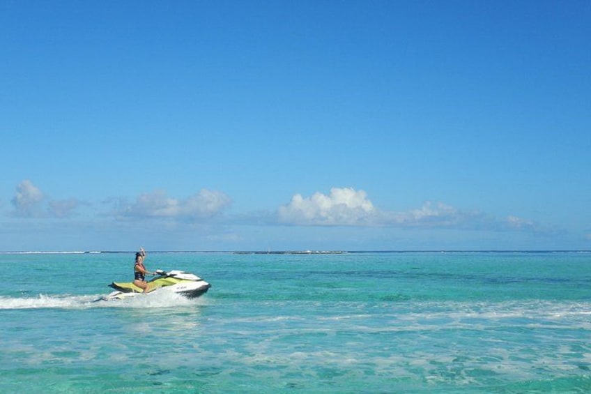 A person riding a jet ski on turquoise water with a clear sky. 3