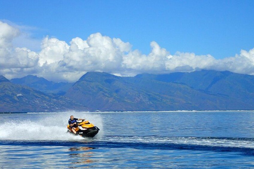 A person riding a jet ski on a body of water with mountains in the background. 3