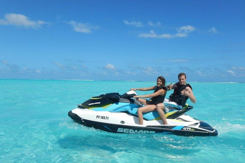 Two people jet skiing on turquoise water with a clear sky. 5