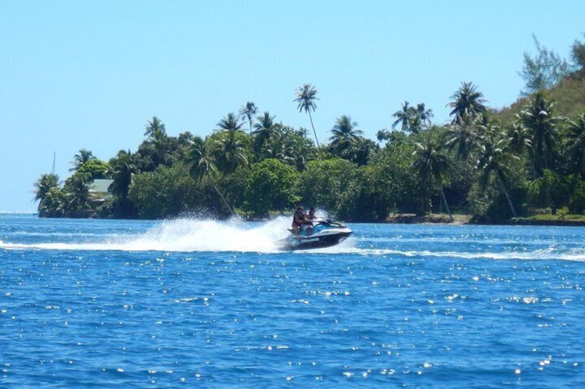 A speedboat on a clear blue sea with a tropical island in the background. 5