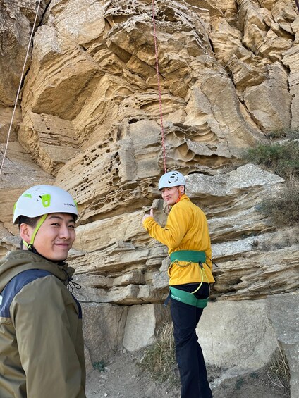 Two people climbing a rocky cliff with ropes. 3
