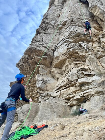Two climbers ascending a rocky cliff with ropes. 2