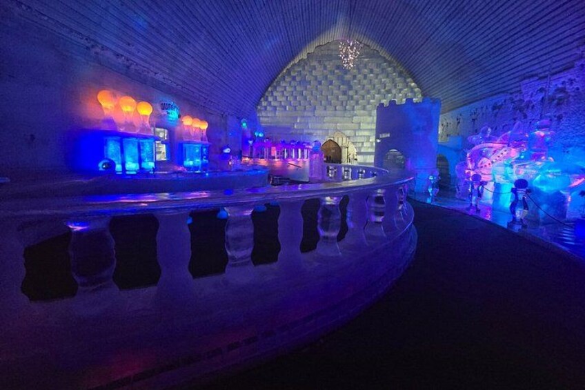 Interior de un hotel de hielo con esculturas de hielo iluminadas y una estructura similar a un castillo. 5