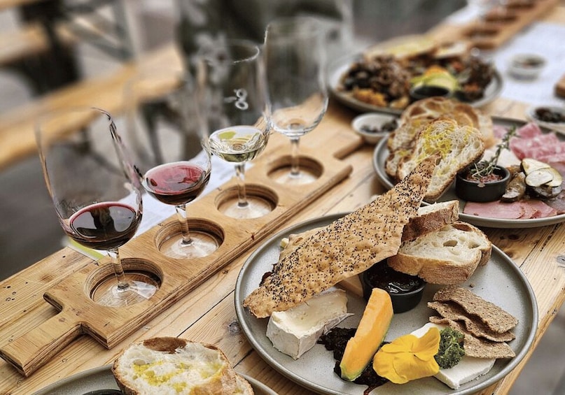 A wooden board with various cheeses, bread, and wine glasses. 4