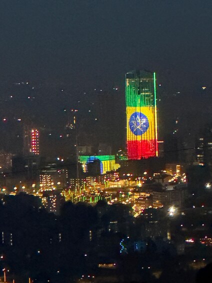 A cityscape at night with a prominent building displaying the Brazilian flag. 3